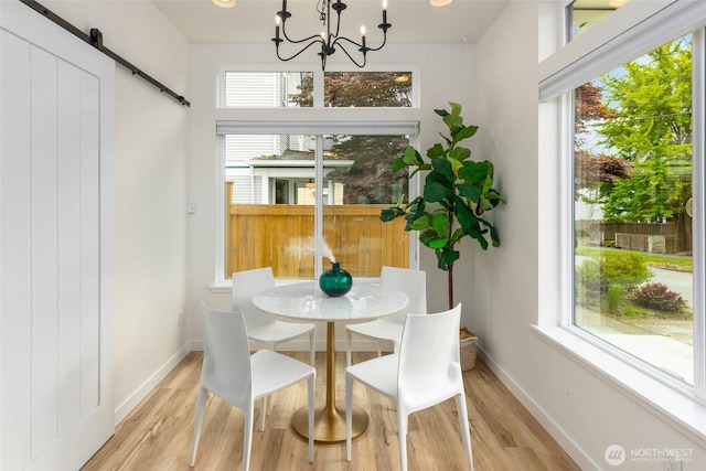 dining room featuring a barn door, a chandelier, wood finished floors, and baseboards