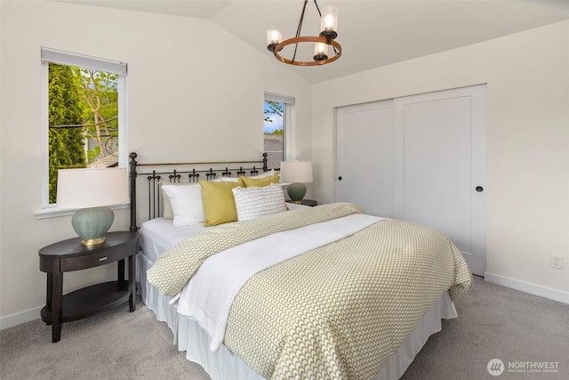 bedroom featuring vaulted ceiling, a closet, light colored carpet, a chandelier, and baseboards