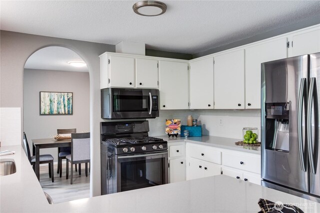 16016 NE 41st St, Vancouver, WA 98628 - kitchen with stainless steel appliances, arched walkways, light countertops, white cabinets, and a textured ceiling
