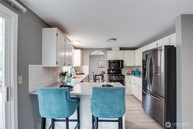 16016 NE 41st St, Vancouver, WA 98628 - kitchen featuring stainless steel appliances, arched walkways, a peninsula, decorative backsplash, and a sink