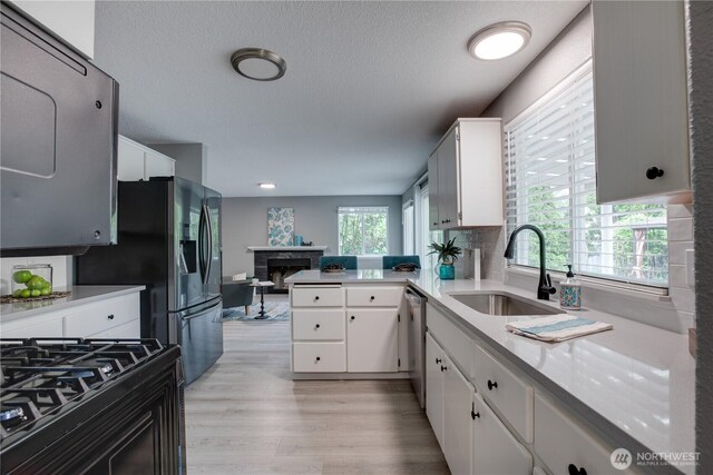 16016 NE 41st St, Vancouver, WA 98628 - kitchen featuring a sink, a fireplace, light wood-type flooring, white cabinetry, and a textured ceiling