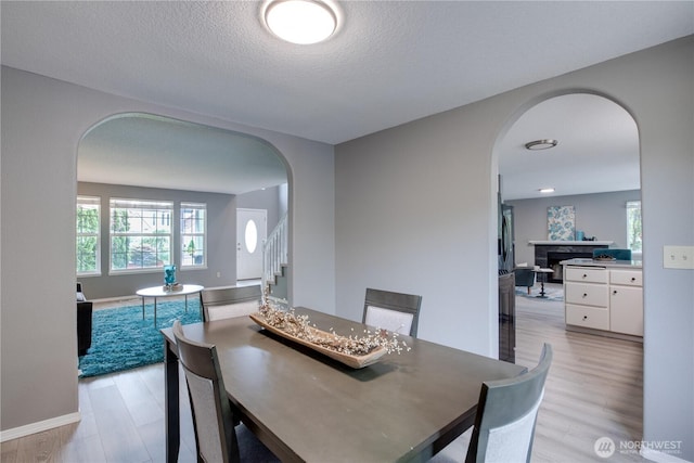16016 NE 41st St, Vancouver, WA 98628 - dining room with arched walkways, light wood-style flooring, stairway, a textured ceiling, and baseboards