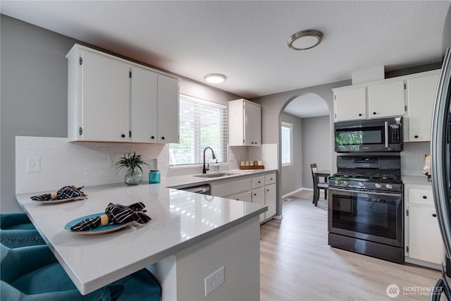 16016 NE 41st St, Vancouver, WA 98628 - kitchen with stainless steel gas stove, a sink, arched walkways, a peninsula, and light wood-type flooring