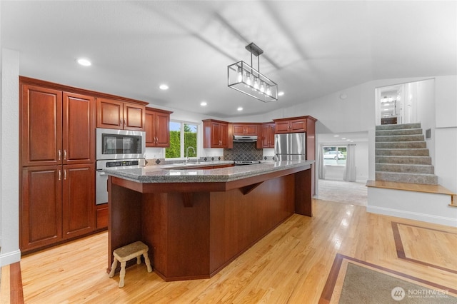 16912 49th St E, Lake Tapps, WA 98391 - kitchen with stainless steel appliances, under cabinet range hood, a breakfast bar, a sink, and lofted ceiling