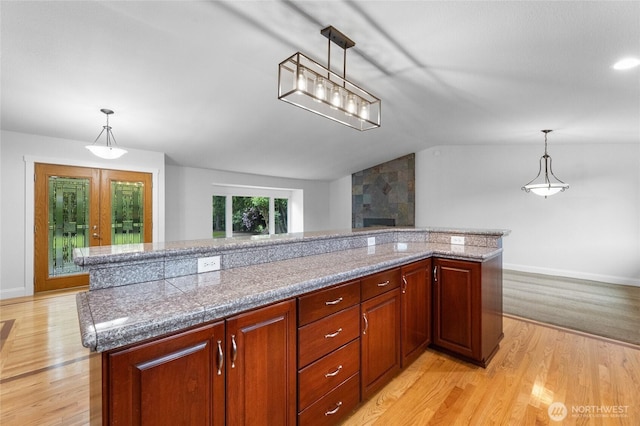 16912 49th St E, Lake Tapps, WA 98391 - kitchen featuring vaulted ceiling, light wood finished floors, a large fireplace, baseboards, and decorative light fixtures