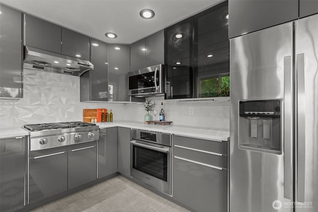 430 S 201st St, Des Moines, WA 98198 - kitchen featuring appliances with stainless steel finishes, exhaust hood, gray cabinets, backsplash, and light countertops