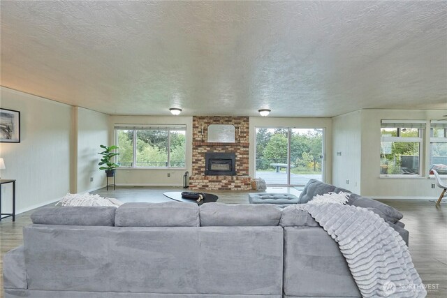 living room with wood finished floors, baseboards, a textured ceiling, and a fireplace