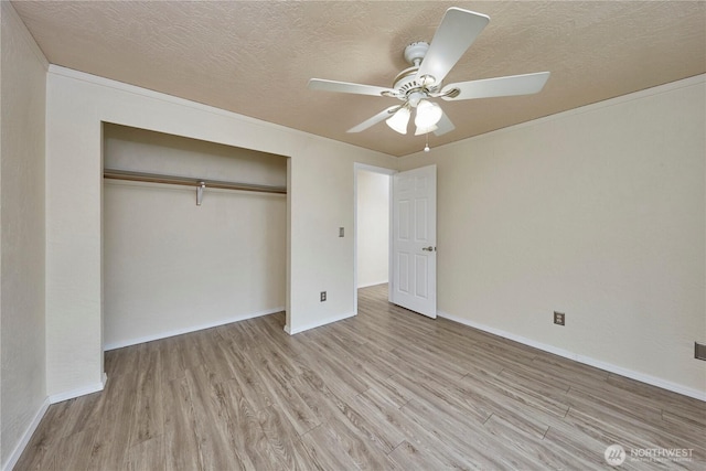 unfurnished bedroom with wood finished floors, a textured ceiling, a closet, and baseboards