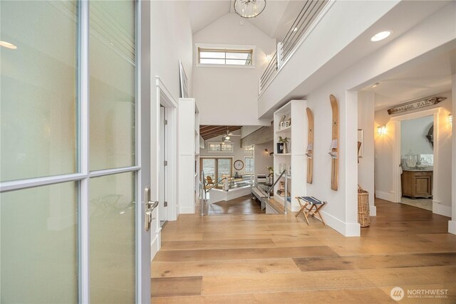 foyer entrance with wood finished floors, high vaulted ceiling, and baseboards