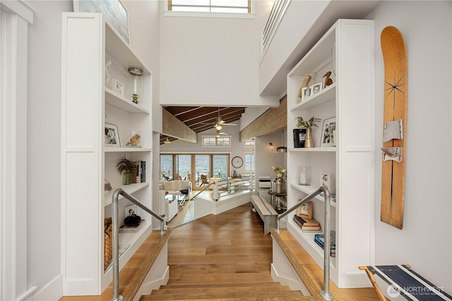 entrance foyer with wood finished floors, a towering ceiling, and a ceiling fan