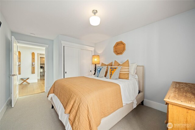 bedroom featuring light colored carpet, baseboards, and a closet