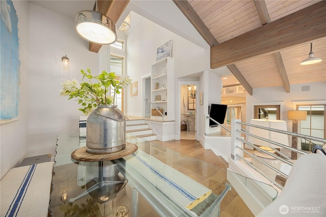 corridor with wood ceiling, beamed ceiling, wood finished floors, an upstairs landing, and high vaulted ceiling