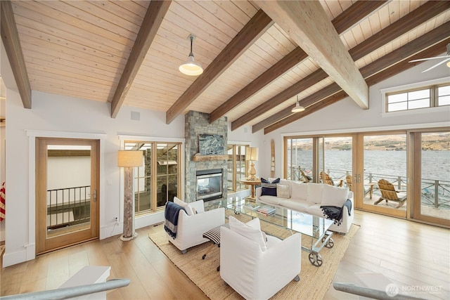 living room featuring beamed ceiling, wood ceiling, light wood-type flooring, a water view, and a fireplace