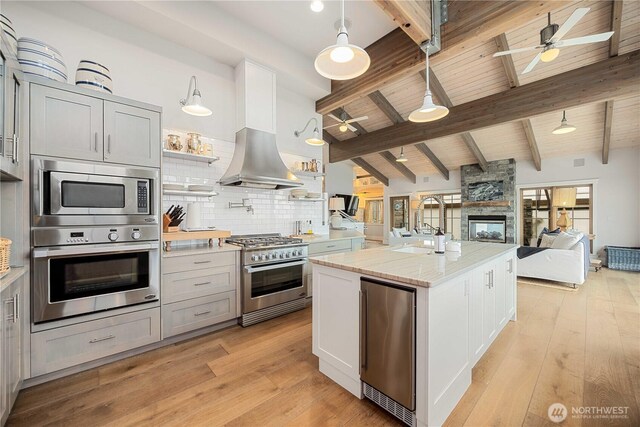 kitchen with stainless steel appliances, a multi sided fireplace, open floor plan, ceiling fan, and tasteful backsplash