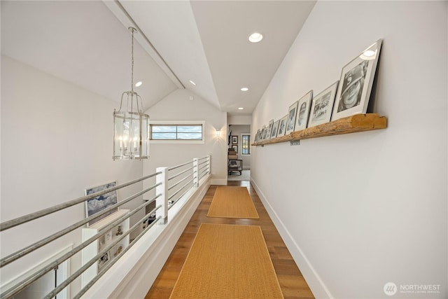 corridor with a chandelier, lofted ceiling, wood finished floors, recessed lighting, and baseboards