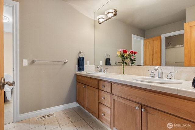 full bath featuring tile patterned floors, double vanity, and baseboards