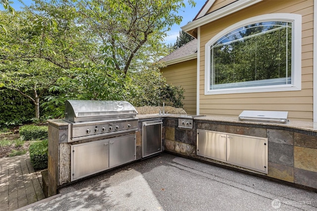 view of patio / terrace featuring exterior kitchen and a grill