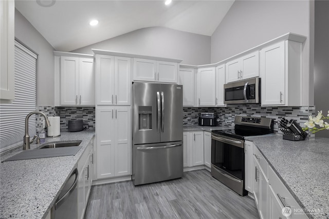 5036 Chambers Creek Loop, Olympia, WA 98501 - kitchen with stainless steel appliances, a sink, vaulted ceiling, white cabinetry, and decorative backsplash