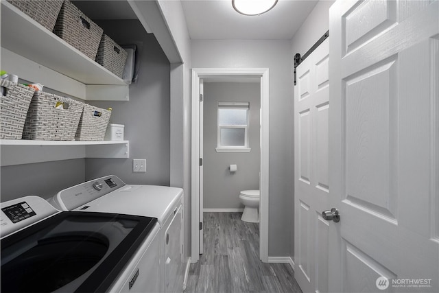5036 Chambers Creek Loop, Olympia, WA 98501 - clothes washing area featuring washer and clothes dryer, wood finished floors, baseboards, and a barn door