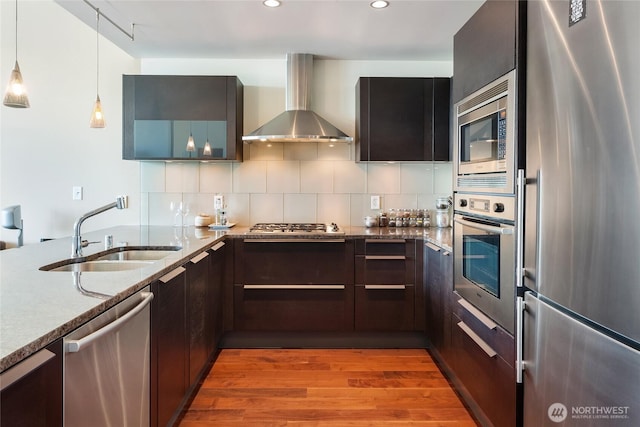 737 Olive Way Unit 2703, Seattle, WA 98101 - kitchen with stainless steel appliances, wall chimney range hood, light stone countertops, light wood finished floors, and backsplash