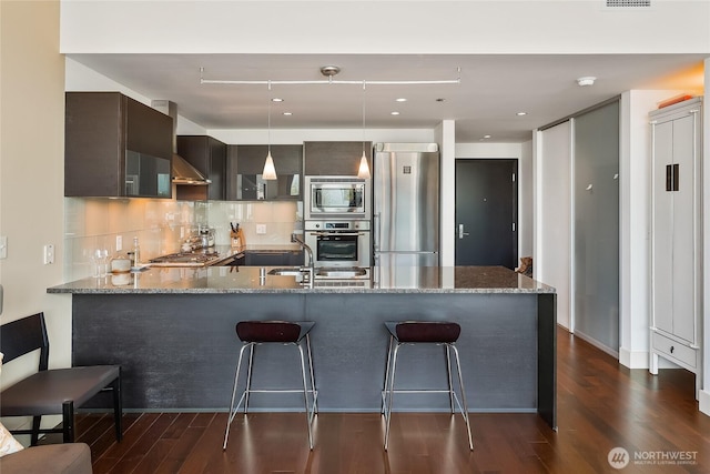 737 Olive Way Unit 2703, Seattle, WA 98101 - kitchen featuring stainless steel appliances, a peninsula, dark wood-style floors, dark brown cabinetry, and stone counters