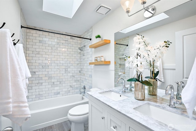 bathroom featuring shower / bathtub combination, toilet, double vanity, a skylight, and wood finished floors
