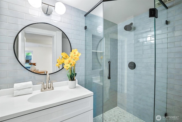bathroom featuring a stall shower, tile walls, and vanity