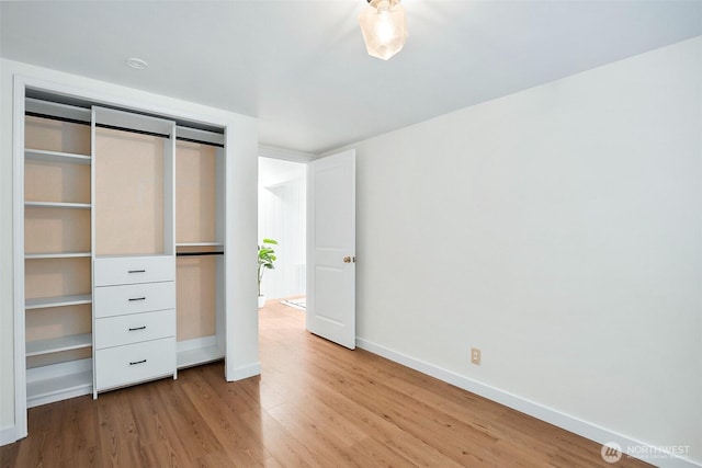 unfurnished bedroom featuring light wood-style floors, baseboards, and a closet