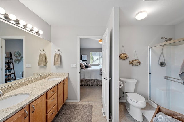 ensuite bathroom with toilet, a shower stall, double vanity, and baseboards