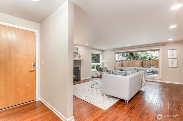 living area featuring hardwood / wood-style flooring, a fireplace with flush hearth, baseboards, and recessed lighting