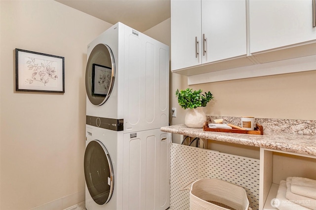 clothes washing area featuring cabinet space and stacked washer / dryer