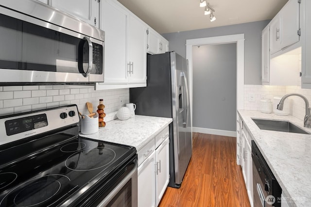 610 Aloha St Unit 303, Seattle, WA 98109 - kitchen with appliances with stainless steel finishes, a sink, baseboards, light wood finished floors, and white cabinets