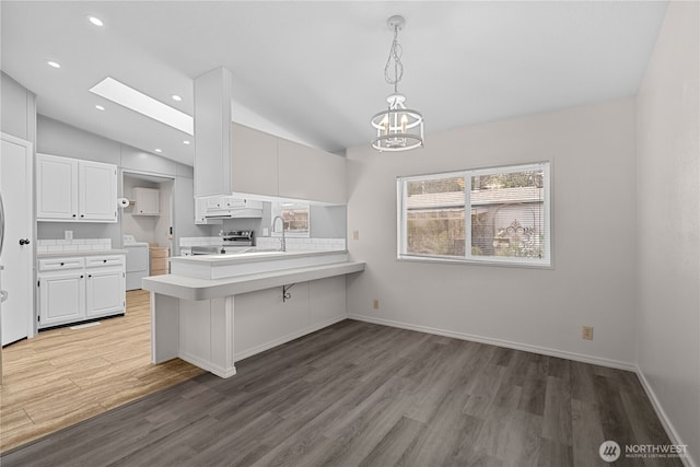 kitchen with separate washer and dryer, lofted ceiling, wood finished floors, light countertops, and white cabinets