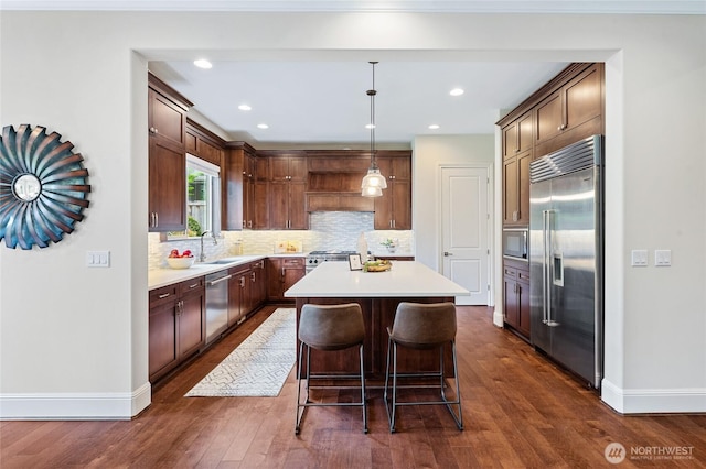 9827 NE 20th St, Bellevue, WA 98004 - kitchen featuring built in appliances, a sink, a kitchen island, baseboards, and tasteful backsplash