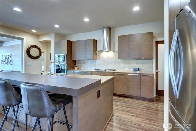 13406 SE 262nd St, Kent, WA 98042 - kitchen with appliances with stainless steel finishes, wall chimney exhaust hood, light wood-style floors, a kitchen breakfast bar, and a sink
