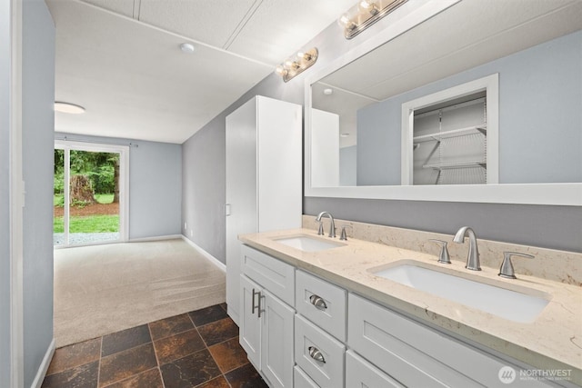 full bathroom with stone finish flooring, double vanity, and baseboards