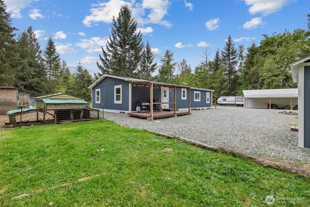 22011 167th St E, Orting, WA 98360 - rear view of property with a lawn, a deck, exterior structure, an outdoor structure, and view of scattered trees
