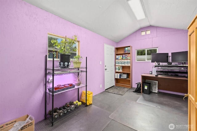home office with lofted ceiling and concrete flooring