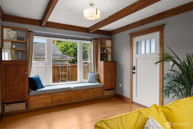foyer featuring beam ceiling, light wood-style flooring, and baseboards