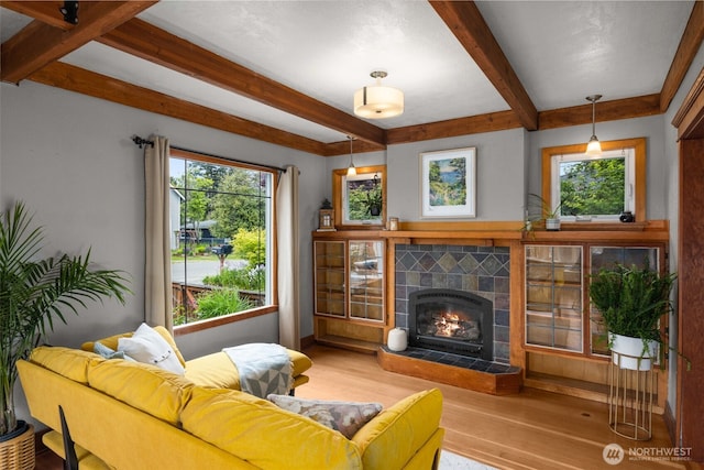 living area featuring wood finished floors, beamed ceiling, and a tile fireplace