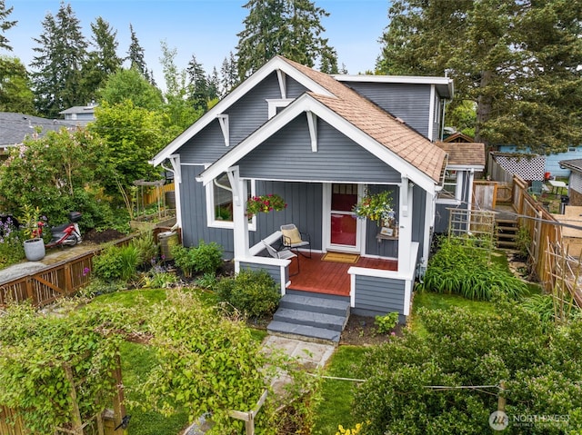 view of front of home featuring fence, board and batten siding, roof with shingles, and covered porch