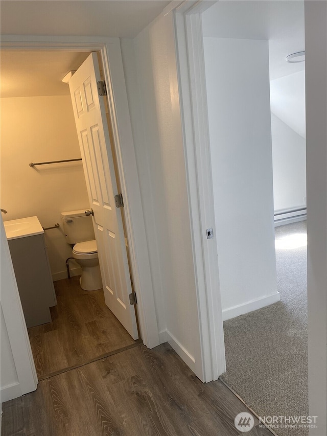 bathroom with toilet, baseboards, a baseboard radiator, wood finished floors, and vanity