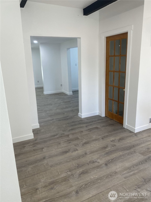 hall featuring baseboards, wood finished floors, and beam ceiling