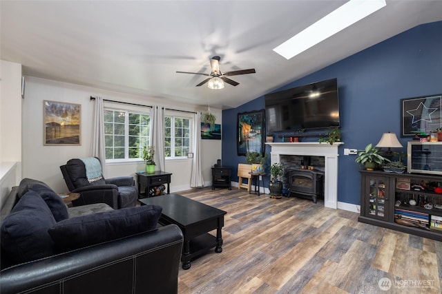 12128 167th Dr NE, Arlington, WA 98223 - living room featuring a wood stove, vaulted ceiling, ceiling fan, wood finished floors, and a skylight