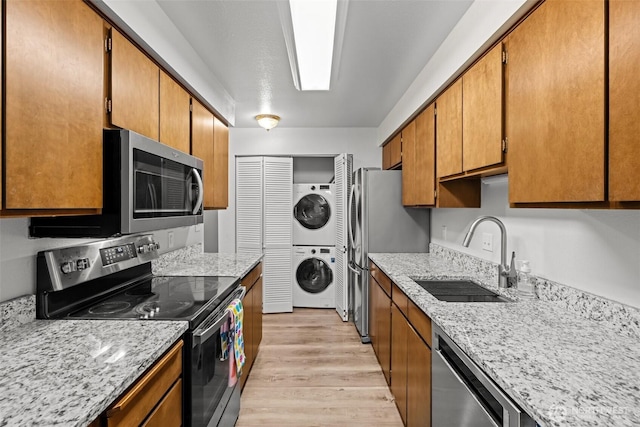 8516 196th St SW Unit 311, Edmonds, WA 98026 - kitchen featuring appliances with stainless steel finishes, stacked washer / dryer, a sink, light wood-style floors, and brown cabinets