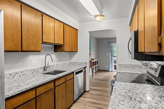 8516 196th St SW Unit 311, Edmonds, WA 98026 - kitchen with appliances with stainless steel finishes, a sink, light wood-type flooring, brown cabinetry, and light stone countertops