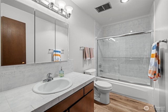8516 196th St SW Unit 311, Edmonds, WA 98026 - full bath featuring wood finished floors, toilet, backsplash, shower / bath combination with glass door, and vanity