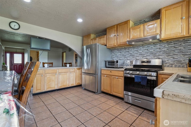 237 Reeds Rd, Touchet, WA 99360 - kitchen with stainless steel appliances, under cabinet range hood, light countertops, light tile patterned flooring, and decorative backsplash