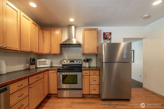 kitchen featuring appliances with stainless steel finishes, wall chimney exhaust hood, dark countertops, light wood-style flooring, and recessed lighting