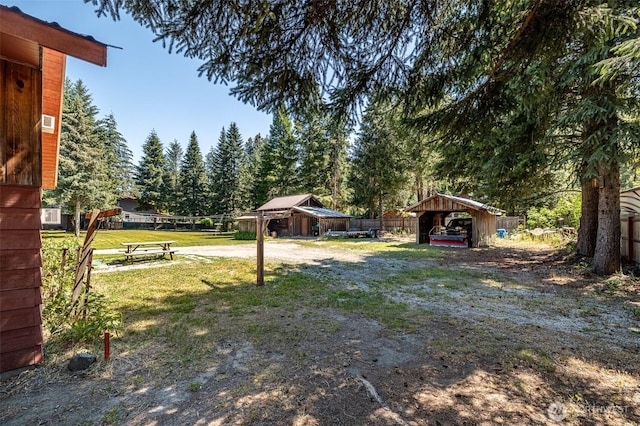 view of grassy yard with a carport and dirt driveway
